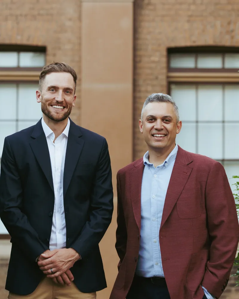 Andy Crebar and Heath smiling outside a sandstone building