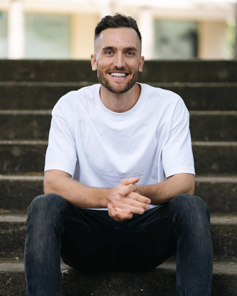 Andy Crebar sitting on outdoor steps, laughing